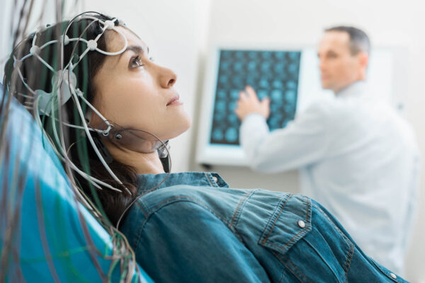 A patient sits reclined with a device for Electroencephalogram on her head
